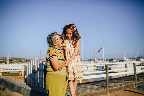 A grandma and her granddaughter embracing at a dock by the beach