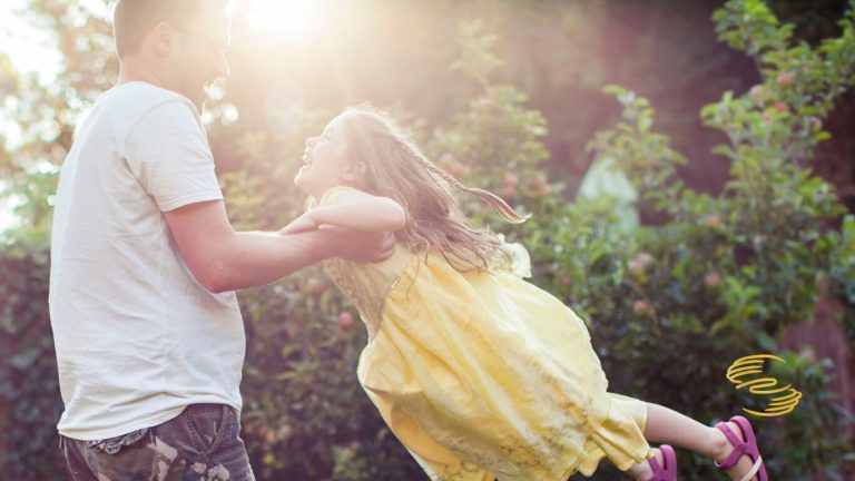 Father swinging his daughter around joyfully outdoors