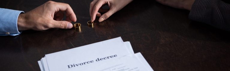 Two people signing divorce decree and taking their wedding rings off