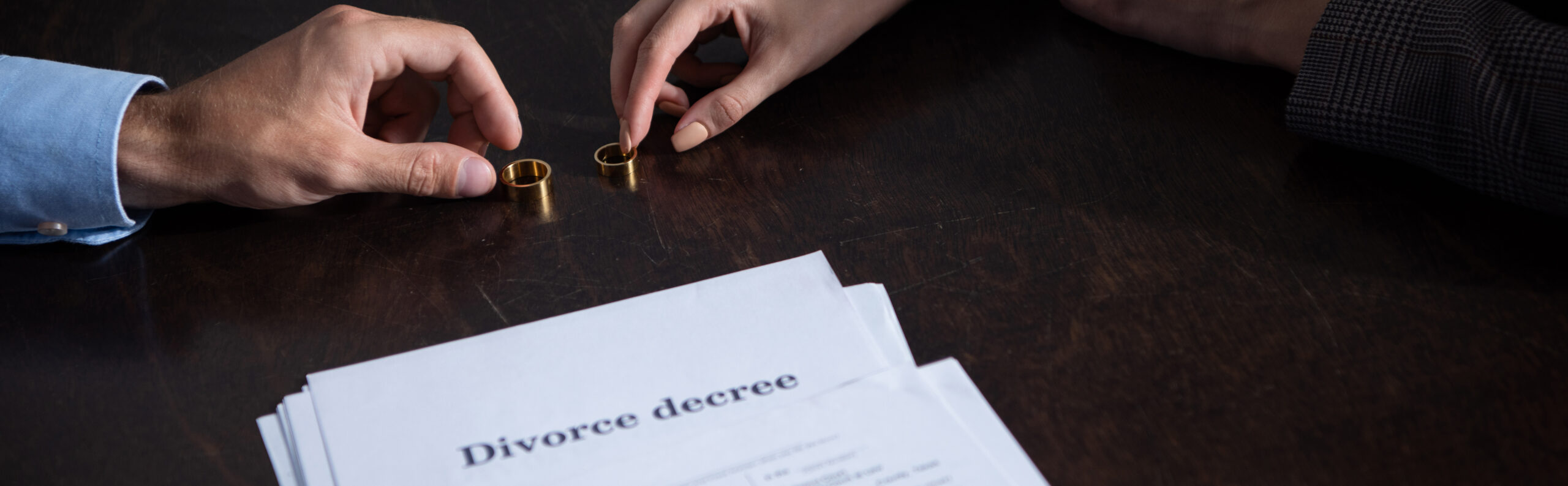 Two people signing divorce decree and taking their wedding rings off